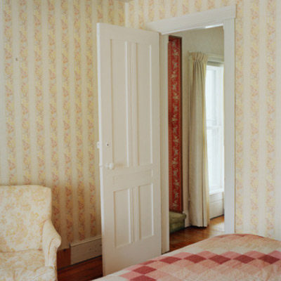 bedroom with an open door and yellow and white wallpaper