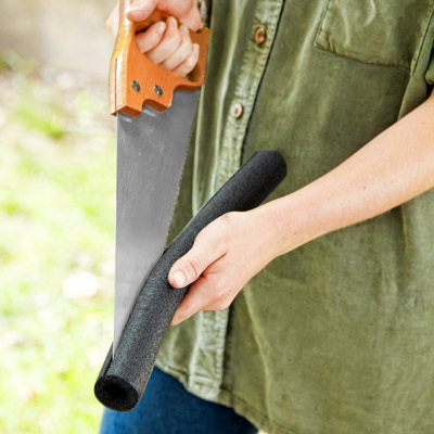 woman sliding pipe insulation on teeth of handsaw