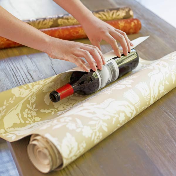 Using an empty wine bottle as a spool to roll kinks out of wallpaper