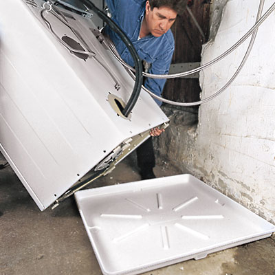 worker moves a washer onto a washer drain pan