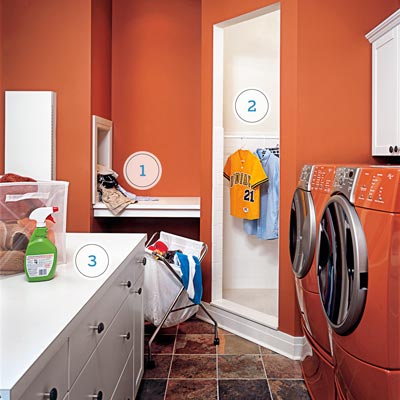 a laundry room with red walls, laundry chute, shower stall and island