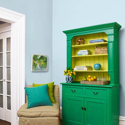 a room with a blue wall and green vintage hutch
