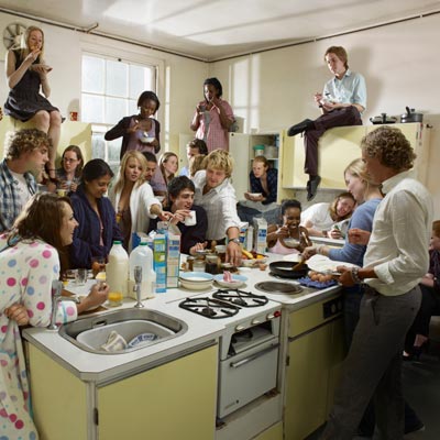 a large group of people in kitchen eating and talking