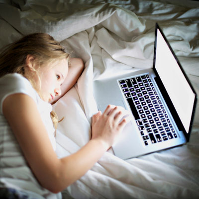 girl on laptop in the dark in her bed