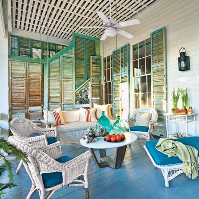 a porch with many salvaged shutters, a ceiling fan and cool blue painted floor