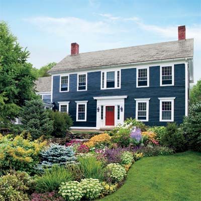 diversity of plants and flowers planted in a dramatic entry garden in front a blue house