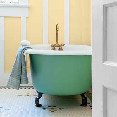 bungalow house bath with old tub painted to match green accents in hex-tile floor 