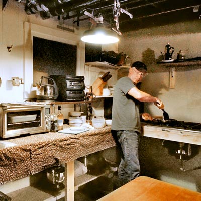 homeowner Don Post cooking in temporary basement kitchen during kitchen remodel