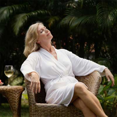 women lounging in chair with glass of wine for 23 Ways to Turn Your Home Into a Staycation Resort