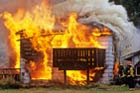 house on fire with fire fighters putting it out with water