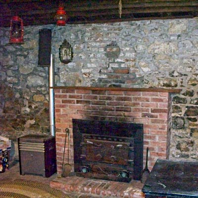 kitchen with original stone walls, exposed wood ceiling beams and fireplace in save this old house lexington, missouri greek revival 