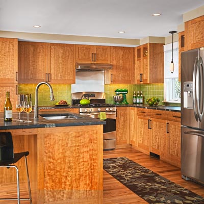 kitchen with cherry veneer over fiberboard cabinets, bronze pulls, soapstone countertops and green glass-tile backsplash 