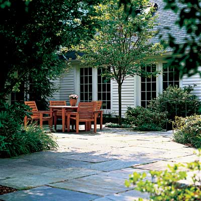 bluestone terrace patio with seating area bordered by curved planting beds and trees