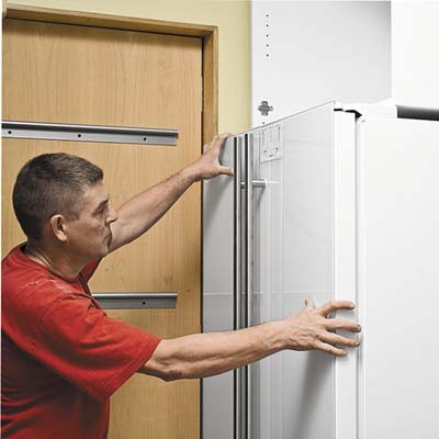 men lining cabinet fronts with fridge door