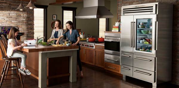 family in kitchen with glass-front refrigerator