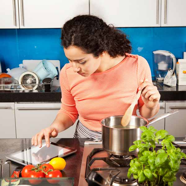 woman looking up healthy recipes on her iPad while cooking in kitchen