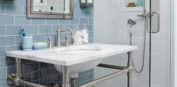small chrome and blue tile bathroom with freestanding glass shower