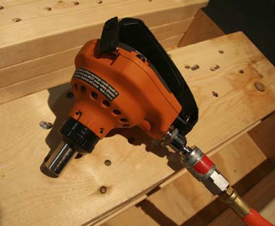 Rigid pneumatic palm nailer attached to compressor hose