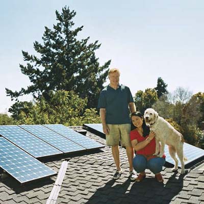 a couple and their dog stand on the roof ot their solar-paneled roof
