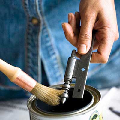 brush applies shellac to hinge over a can of shellac