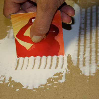 gift card customized to be used as a trowel spreading mastic on a tile