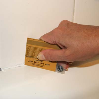gift card being used to wipe away excess grout in a tiled tub surround