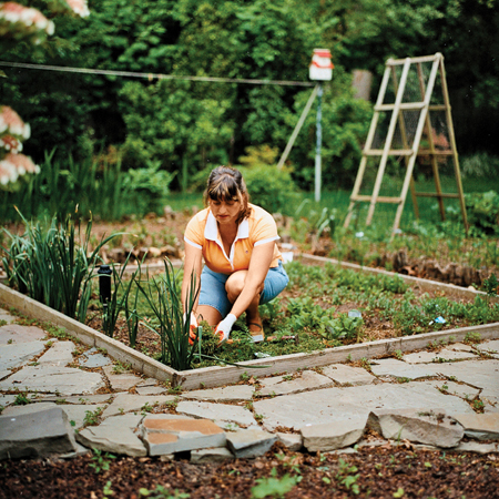 homeowner, Rosi Zingales kneeling in her vegetable garden