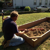 Roger Cook uses a 4-foot level to make sure the raised garden bed frame is level in the soil