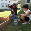 Roger Cook drives stakes in to reinforce the raised garden bed frame