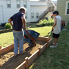 Roger Cook fills the raised garden bed frame with fresh soil using a wheelbarrow