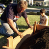 Roger Cook reattaches the last board of the raised garden bed frame