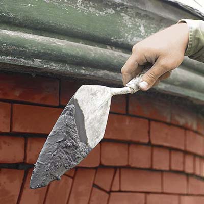 mixing mortar to apply to a brick wall