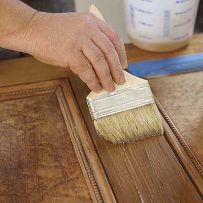 John Thomas paints a thick coat of commercial stripper on wood