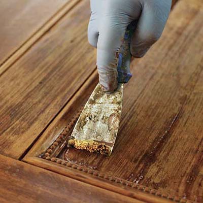A dull scraper is the best tool for removing stripper-softened finish from flat panels