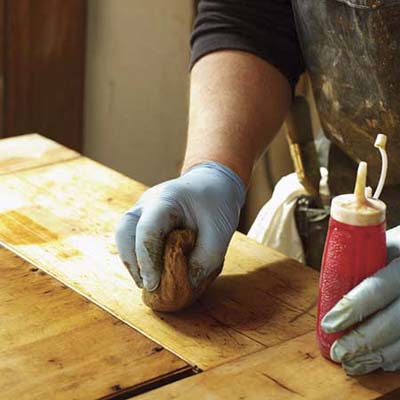 John Thomas rubs the stripped wood with fine steel wool and denatured alcohol