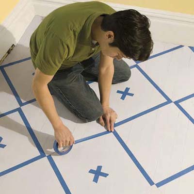masking the checker pattern on a floor with painter's tape