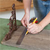 hands using a combination square to draw a line across the center of the mounting board to make a vintage porcelain tap towel rack