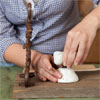 hands attaching a tap to the base mounted on a board to make a vintage porcelain tap towel rack