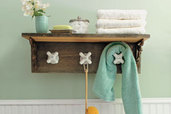 completed towel rack made from vintage taps with shelf installed in a green bathroom