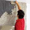man covering the lath of a fireplace with motar to create a stone veneer surround