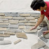 man laying out the stones he'll use to create a stone veneer surround