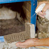 hand with spray bottle wetting down the stone and wall used to create a stone veneer fireplace surround