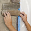 hands installing the rest of the corner pieces to create a stone veneer fireplace surround