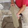 hands coating the top-left fieldstone to create a stone veneer fireplace surround