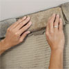 hands installing the first course of stone to create a stone veneer fireplace surround