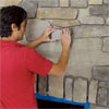 man installing the rest of the stone in courses from top down to create a stone veneer fireplace surround