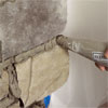 the tip of a grout bag applying grout to the stone when creating a stone veneer fireplace surround