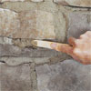 a hand using a striking tool to carve the grout when creating a stone veneer fireplace surround