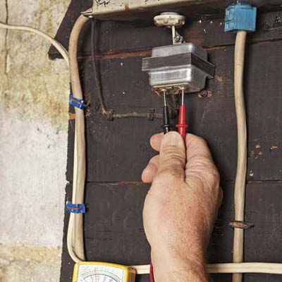 electrician testing doorbell transformer with multimeter
