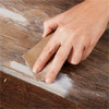 hand sanding down dry wood putty on a cabinet door